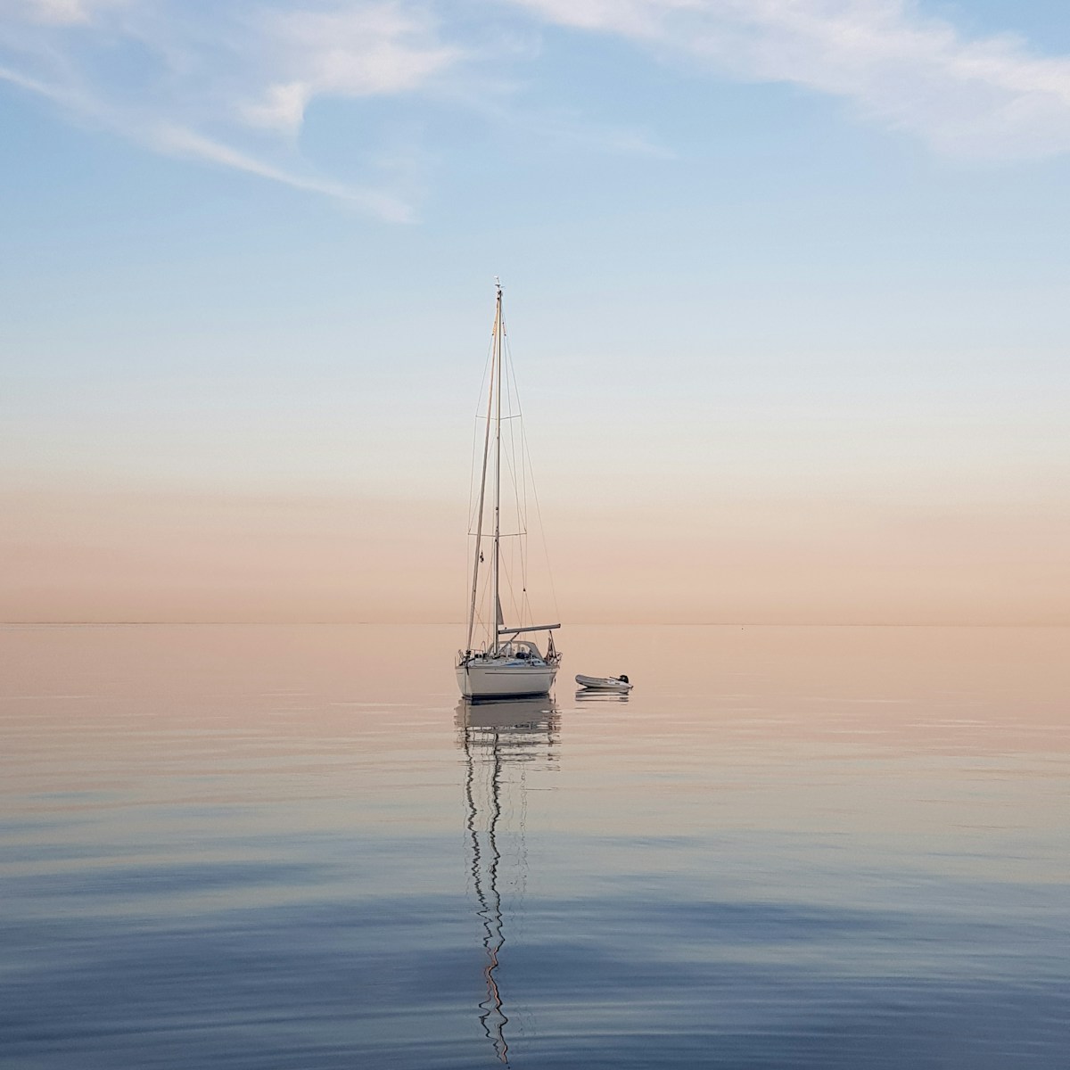 Zeilboot op kalm water bij zonsopgang
