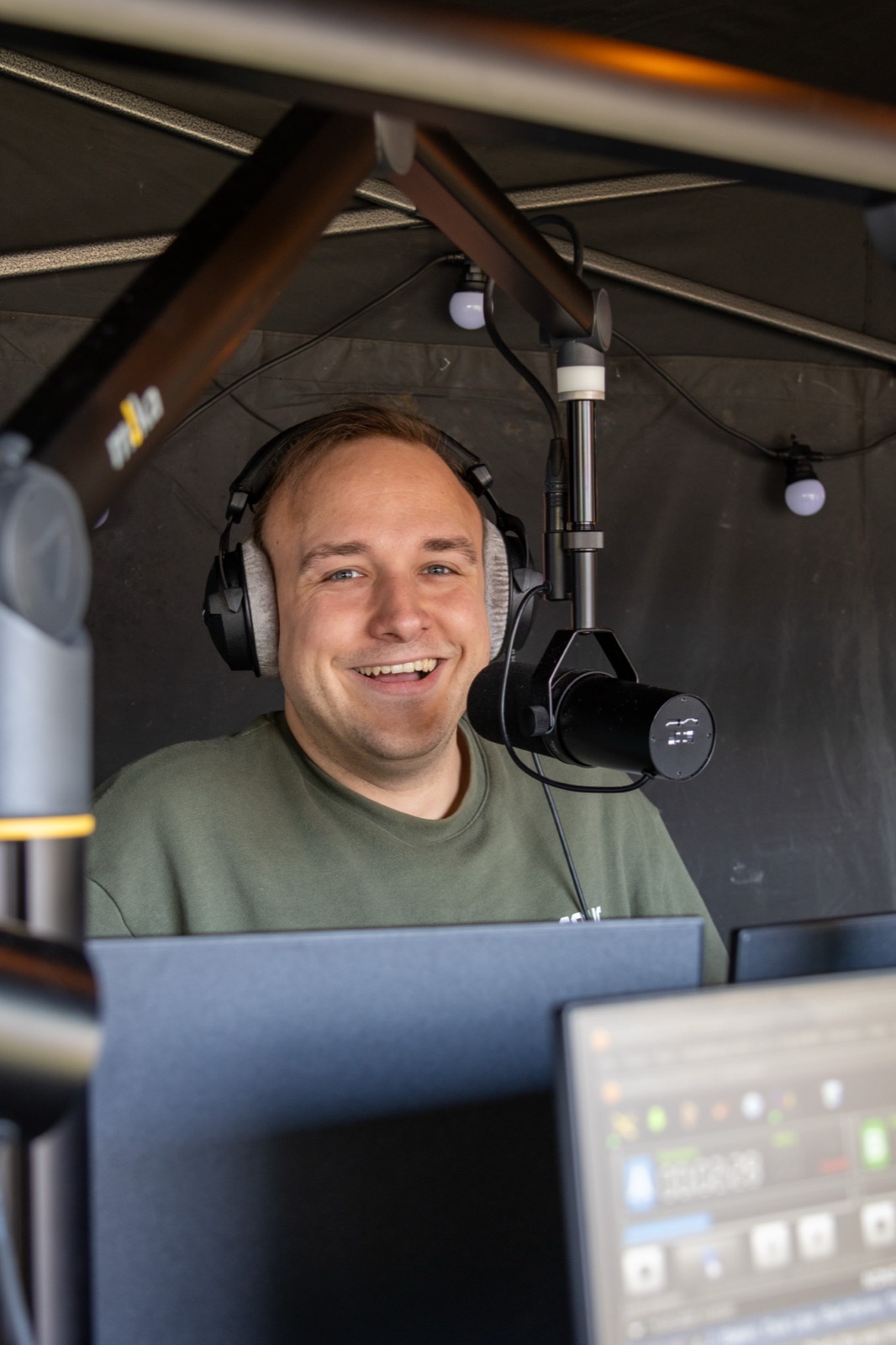 Presentator in de mobiele radiostudio met Shure SM7b en koptelefoon